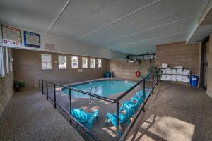 a large swimming pool with blue chairs in a building at Moose Creek Lodge & Suites in Cody