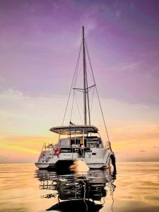 een witte boot in het water bij zonsondergang bij Sabba Whitesand Catamaran in Fodhdhoo