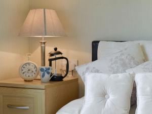a bed with a lamp and a clock on a night stand at Willow in Thornbury