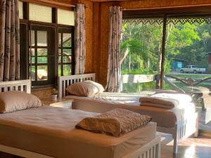 Duas camas num quarto com uma janela em วังภูไพร ฟาร์มสเตย์ em Wang Nam Khieo