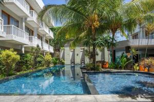 a swimming pool in front of a building with palm trees at Abian Harmony Hotel in Sanur