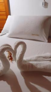 a pair of towels on a white bed with a mess at Cantinho da Luna in Morro de São Paulo