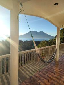 a hammock on a balcony with a view of the ocean at Hotel Berena in San Marcos La Laguna