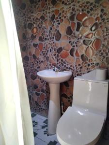 baño con lavabo y aseo con pared de piedra. en Hotel Berena, en San Marcos La Laguna