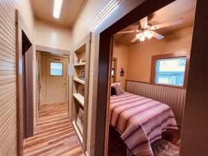 um pequeno quarto com uma cama e uma ventoinha de tecto em Texas Blue Apple Cottage em Medina