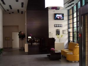 eine Lobby mit einem gelben Stuhl und einem Fernseher an der Wand in der Unterkunft Hotel Berthelot in Bukarest