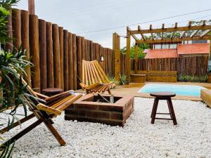 un patio trasero con una hamaca, una valla y una piscina en Casa com Banheira, Piscina e Quadra de Areia en Imbituba