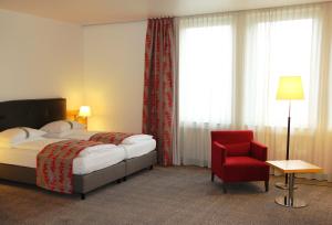 une chambre d'hôtel avec un lit et un fauteuil rouge dans l'établissement Holiday Inn Frankfurt Airport - Neu-Isenburg, an IHG Hotel, à Neu-Isenburg