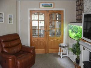 a living room with a brown leather chair and a wooden door at Coastal Retreat - Uk37827 in Bare