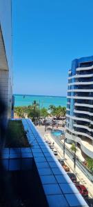 un balcone con vista su un edificio e sulla spiaggia. di NA BEIRA MAR DE PAJUCARA- EDIF NEO- APARTAMENTO QUARTO E SALA - POSSUI VARANDA- VISTA LATERAL DO MAR-RUA JULIO PLECH FILHO 60 ESQUINA COM AVENIDA DOUTOR ANTONIO GOUVEIA - CONSUMO ELETRICO É PAGO No CKECK-OUT - 1 KWH É 1,35 REIAS - TEM TELA DE PROTEÇÃO a Maceió