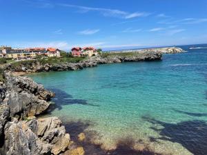 a body of water with rocks and houses in the background at Apartamentos Los Cubos de Llanes 1 in Llanes