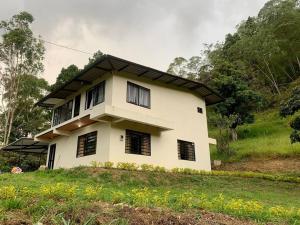 une maison blanche avec des fenêtres noires sur une colline dans l'établissement Lee TODO lo que incluye para Familia (Guateque), à Guateque