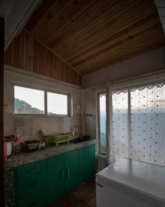 a kitchen with green cabinets and a large window at MiakaHillsDarjeeling in Darjeeling