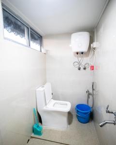 a white bathroom with a toilet and a window at MiakaHillsDarjeeling in Darjeeling