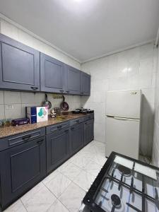 cocina con armarios azules y nevera blanca en Hotel unit in downtown Cairo for rent en El Cairo