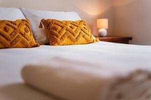 uma cama branca com duas almofadas amarelas em Blayney Retreat-Central & Comfortable em Blayney