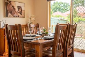 a dining room table with chairs and a table with wine glasses at Blayney Retreat-Central & Comfortable in Blayney