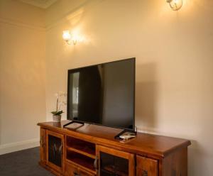 a flat screen tv sitting on top of a wooden entertainment center at Blayney Retreat-Central & Comfortable in Blayney