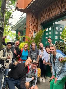 a group of people posing for a picture in front of a building at Hue Sweethouse 1 Homestay in Hue