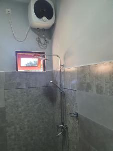 ein Bad mit einer Dusche mit einem Spiegel und einem Fenster in der Unterkunft Belihull Vila in Nuwara Eliya