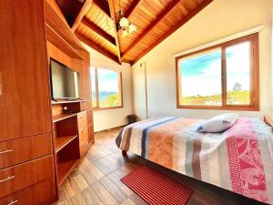 um quarto com uma cama, uma televisão e janelas em ItsaHome Vacations - Casa de Campo Atuntaqui 