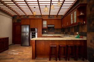 a large kitchen with wooden cabinets and a refrigerator at ItsaHome Vacations - Casa de Campo Atuntaqui 