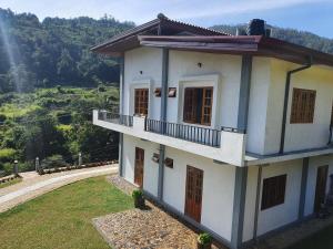 a white house with a balcony on a hill at Belihull Vila in Nuwara Eliya