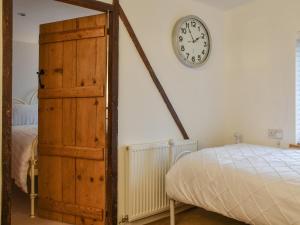 a bedroom with a clock on the wall next to a bed at Pippin Cottage in Bures Saint Mary