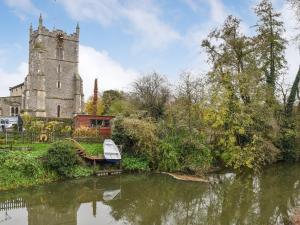 een kerk en een rivier met een boot erin bij Pippin Cottage in Bures Saint Mary