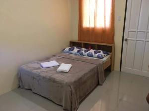 een slaapkamer met een bed met twee handdoeken erop bij Happy Sunset's Inn in Larena