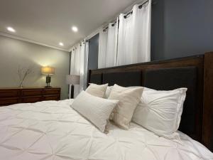 una camera da letto con un grande letto bianco con cuscini bianchi di Le Boutique Great Toronto a Mississauga