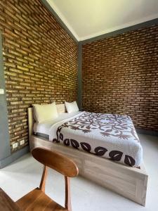 a bed in a room with a brick wall at Panji Hostel in Sukasada