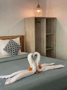 dois cisnes feitos de toalhas numa cama em Hello Penida House em Nusa Penida