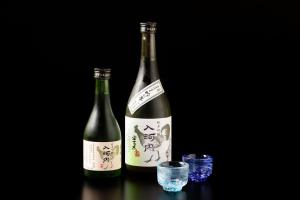 - deux bouteilles de vin assises sur une table avec un verre dans l'établissement 日本の秘境で味わう絶品地鶏 ジローのおうち, à Aki