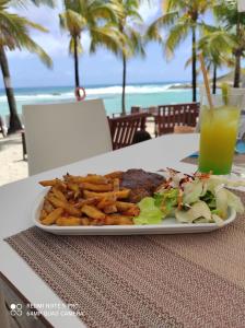 einen Teller mit Pommes frites und einem Drink in der Unterkunft Studio le Sucrier in Saint-François