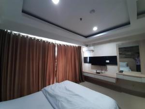 Cozy Tamansari Hive Cawang by Bonzela Property في جاكرتا: غرفة نوم بها سرير ونافذة بها ستارة
