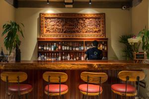 a man standing behind a bar with stools at Khmer House Resort in Siem Reap