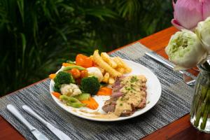 a plate of food with vegetables and meat and french fries at Khmer House Resort in Siem Reap