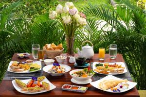 暹粒的住宿－Khmer House Resort，餐桌,带食物、饮料和鲜花的盘子