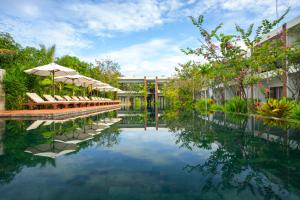 a pool at a resort with chairs and umbrellas at Khmer House Resort in Siem Reap