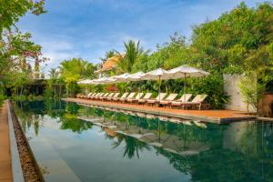 a swimming pool with lounge chairs and umbrellas at Khmer House Resort in Siem Reap