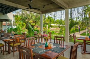暹粒的住宿－Khmer House Resort，一间带木桌椅的餐厅和一个花园
