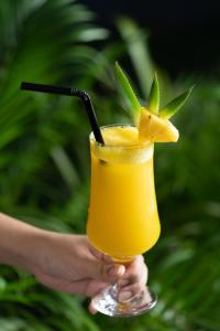 a person holding a glass of orange juice with a pineapple at Khmer House Resort in Siem Reap