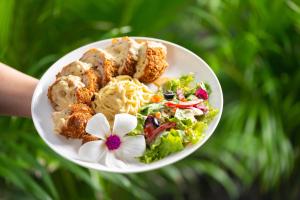 a person holding a plate of food with a salad and a flower at Khmer House Resort in Siem Reap