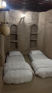 two twin beds in a room with shelves at نزل حارة المسفاة Harit AL Misfah Inn in Misfāh