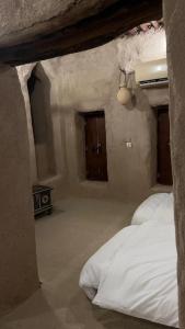 ein Schlafzimmer mit einem weißen Bett in einem Steinzimmer in der Unterkunft نزل حارة المسفاة Harit AL Misfah Inn in Misfāh