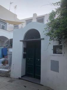 ein weißes Haus mit einer grünen Tür und einem Fenster in der Unterkunft Nicola’s house in Procida