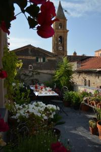 un patio con una mesa con flores y una torre de reloj en La Terrazza di Vico Olivi B&B, en Ventimiglia