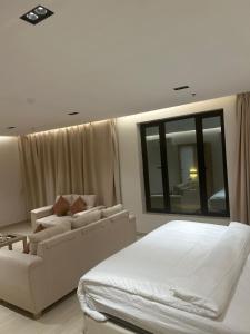 1 dormitorio con cama, sofá y espejo en همس المدى للشقق المخدومه, en Al-Hasa