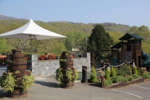 a garden with plants and an umbrella and a playground at Aberdunant Hall in Porthmadog